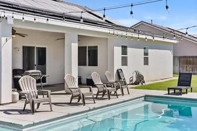 a group of chairs sitting next to a swimming pool at Spacious Home with Private Pool in Bakersfield