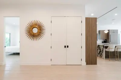 a white living room with white walls and a mirror at Modern Poolside Paradise in Sherman Oaks