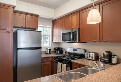 a kitchen with wooden cabinets and a stainless steel refrigerator at Demo2 in Los Angeles