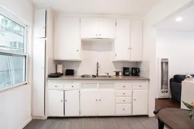 a white kitchen with white cabinets and a window at Affordable 1BR apt near Beverly Hills in Los Angeles