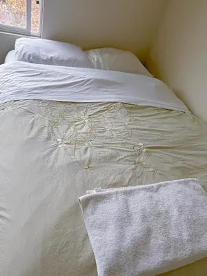 a white bed with white sheets and a towel on it at Big bedroom shared bathroom in Fontana
