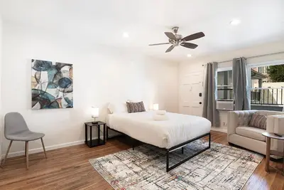 a white bedroom with a bed and a couch at Bright Second-Floor Studio Near Beverly Hills in Los Angeles