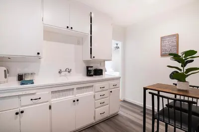 a kitchen with white cabinets and a table and a plant at Bright Second-Floor Studio Near Beverly Hills in Los Angeles