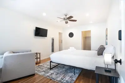 a white bedroom with a bed and a couch at Bright Second-Floor Studio Near Beverly Hills in Los Angeles