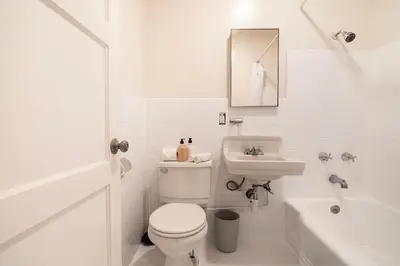 a white bathroom with a toilet and a sink at Bright Second-Floor Studio Near Beverly Hills in Los Angeles