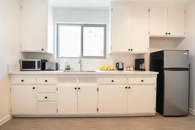 a kitchen with white cabinets and a black refrigerator at Comfortable One-Bedroom with Two Queen Beds in Los Angeles