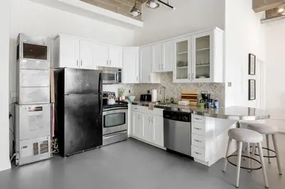 a kitchen with white cabinets and stainless steel appliances at DTLA Boutique Loft w Rooftop Pool Hot Tub in Los Angeles
