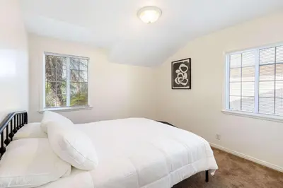 a white bedroom with a bed and two windows at Family Oasis Near Disneyland & Knotts in Downey
