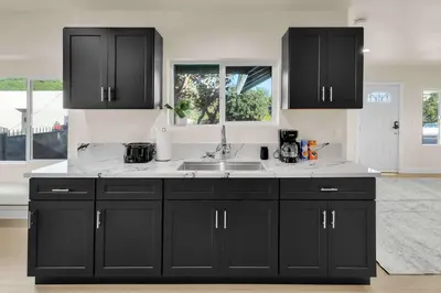 a kitchen with black cabinets and a sink at Stylish LA Retreat Near Disney Knotts SoFi in Paramount
