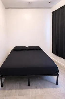 a black bed in a white room with a window at Pickford Vibe near Beverly Hills in Los Angeles