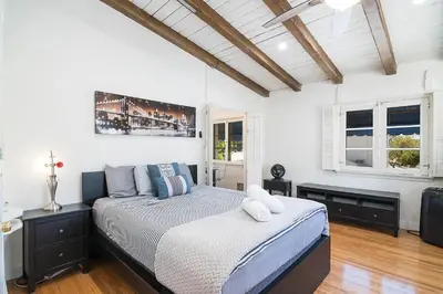 a bedroom with a large bed and two windows at Cozy Beverly Hills Studio Near Shopping with Kitchen in Los Angeles