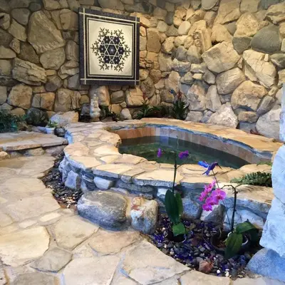a stone wall with a pond in a garden at Family Nature Retreat Near LA with Indoor Grotto Pool in Simi Valley