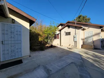 a white house with a garage with a driveway at 2BR Guest Suite With Parking and Garden in Pico Robertson Near Beverly Hills and Cedar Sinai in Los Angeles