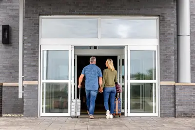 a man and a woman walking into a building at Hyatt Place Ontario Airport in Ontario