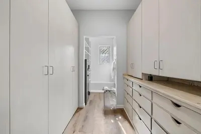 a white kitchen with white cabinets and a wooden floor at The Sinatra House- Fully Furnished! in Los Angeles