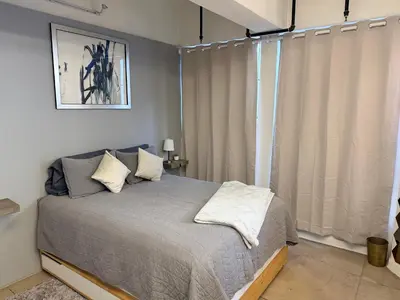 a bedroom with a bed and a window with curtains at Chic urban loft steps from dining and shopping in Los Angeles