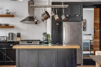 a kitchen with black cabinets and a stainless steel refrigerator at Elegant 3-bedroom home Retreat in East Los Angeles in Los Angeles