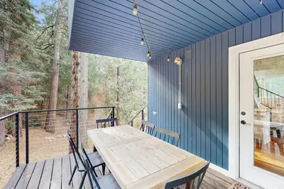 a porch with a wooden table and chairs on a deck at Mountain Playhouse in Lake Arrowhead
