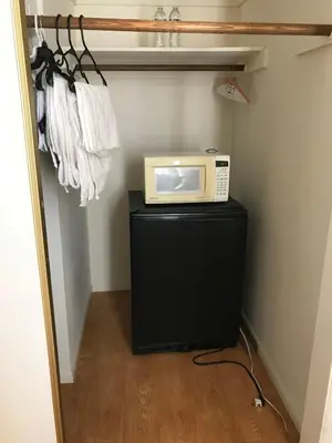 a microwave sitting on top of a black stand in a closet at Fara UCLA in Los Angeles