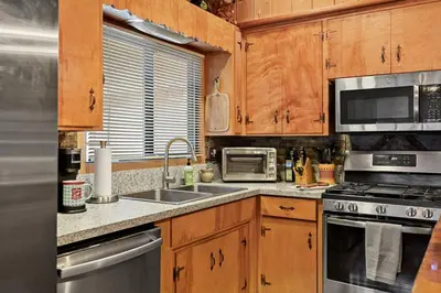 a kitchen with wooden cabinets and stainless steel appliances at Pinecone Den in Big Bear Lake
