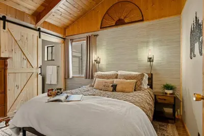 a bedroom with a large bed and a wooden wall at Pinecone Den in Big Bear Lake