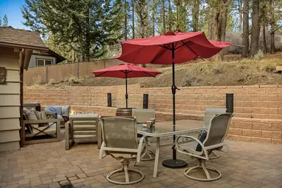 a patio with a table and two red umbrellas at Pinecone Den in Big Bear Lake