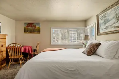 a bedroom with a white bed and a table and chairs at Snuggle Down Cottage in Big Bear Lake