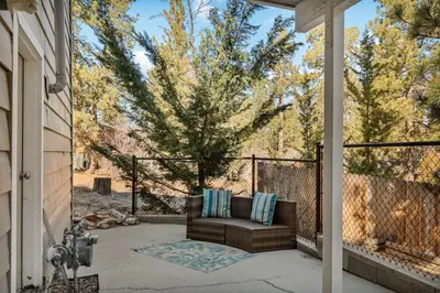 a patio with a couch and a tree at Snuggle Down Cottage in Big Bear Lake