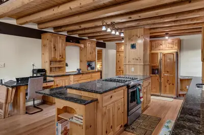 a kitchen with wooden cabinets and a stove top oven at Vista Lodge! 20 min to Silverwood Lake in Cedarpines Park