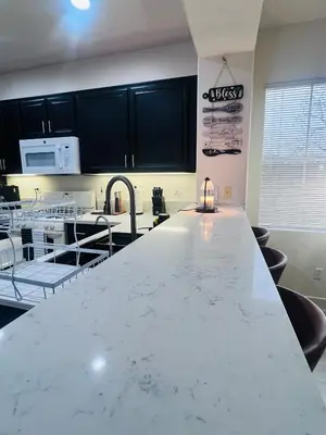 a large kitchen with white counter tops and black cabinets at Stylish & Fully Renovated Home! in Oxnard