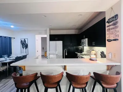 a kitchen with a white counter and brown chairs at Stylish & Fully Renovated Home! in Oxnard