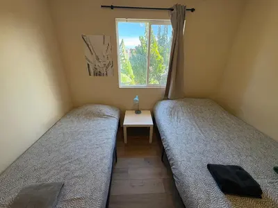 two beds in a small room with a window at Blue Urban Stay LA in Los Angeles