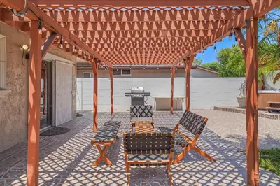 a pergola with two chairs and a grill at Spacious 5 Bedroom Home Near Disneyland & Knotts with Jacuzzi Spa in Norwalk