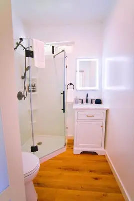 a white bathroom with a shower and a toilet at The Sycamore Suite in Santa Clarita