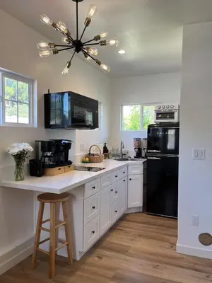 a kitchen with white cabinets and a black refrigerator at The Sycamore Suite in Santa Clarita