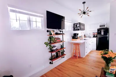 a kitchen with white walls and a black refrigerator at The Sycamore Suite in Santa Clarita