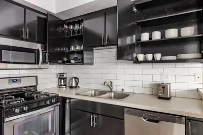 a kitchen with black cabinets and a sink at Blueground Hollywood gym AC nr Runyon LAX-1344 in Los Angeles