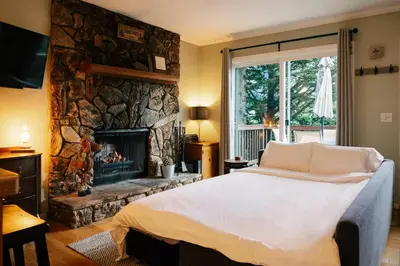a bedroom with a bed and a stone fireplace at Peaceful Mountain Sanctuary near Arrowhead Village in Lake Arrowhead