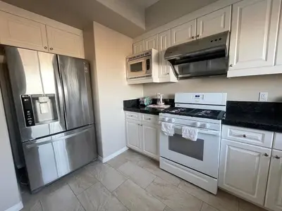 a kitchen with white cabinets and stainless steel appliances at Spacious 2 Bed, 2-Bath Apartment in Monterey Park in Monterey Park