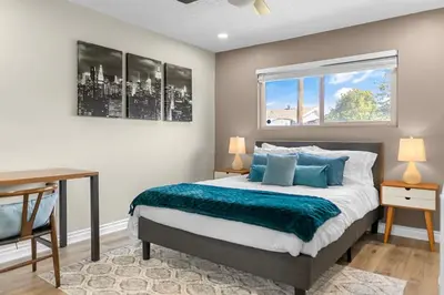 a bedroom with a bed with blue pillows and a window at Near LLU Hospital Calm 3BR Workspace in Loma Linda