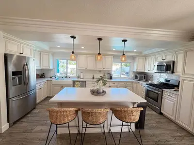 a kitchen with white cabinets and a table with chairs at Peace of Paradise - Heated Pool, Spa & Fireplace in Simi Valley