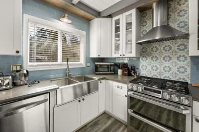 a kitchen with white cabinets and a sink and a stove at Mockingbird Retreat - Walk to the Lake, hot tub, EV charger, Fenced yard. in Big Bear Lake