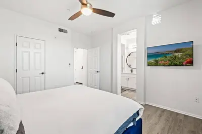 a white bedroom with a bed and a ceiling fan at Newly Remodeled 2BR Apt | Mins to Disney | Arcade in Placentia