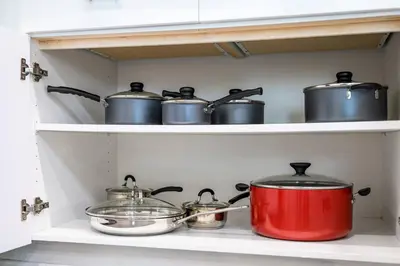 a group of pots and pans on a shelf in a kitchen at Newly Remodeled 2BR Apt | Mins to Disney | Arcade in Placentia