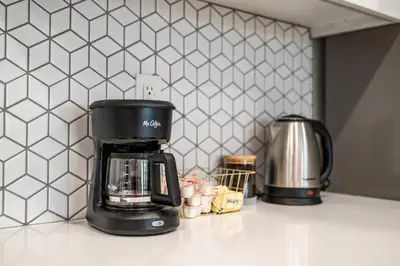a black coffee maker on a counter in a kitchen at Newly Remodeled 2BR Apt | Mins to Disney | Arcade in Placentia