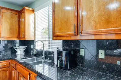 a kitchen with wooden cabinets and a sink at BBQ Ready Home 7 Mi to The Park at River Walk in Bakersfield