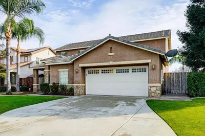 a house with a white garage door in a yard at BBQ Ready Home 7 Mi to The Park at River Walk in Bakersfield