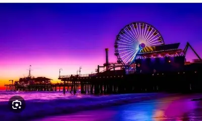 a ferris wheel on the beach next to a pier at Walk to Santa Monica Beach & Pier Boardwalk in Los Angeles