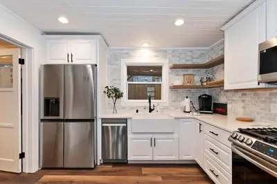 a kitchen with white cabinets and a stainless steel refrigerator at Highland Cedar Cabin WHot Tub Close to Village in Big Bear Lake