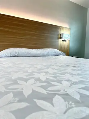 a bed with a white bedspread with flowers on it at Nubell Motel in Bell